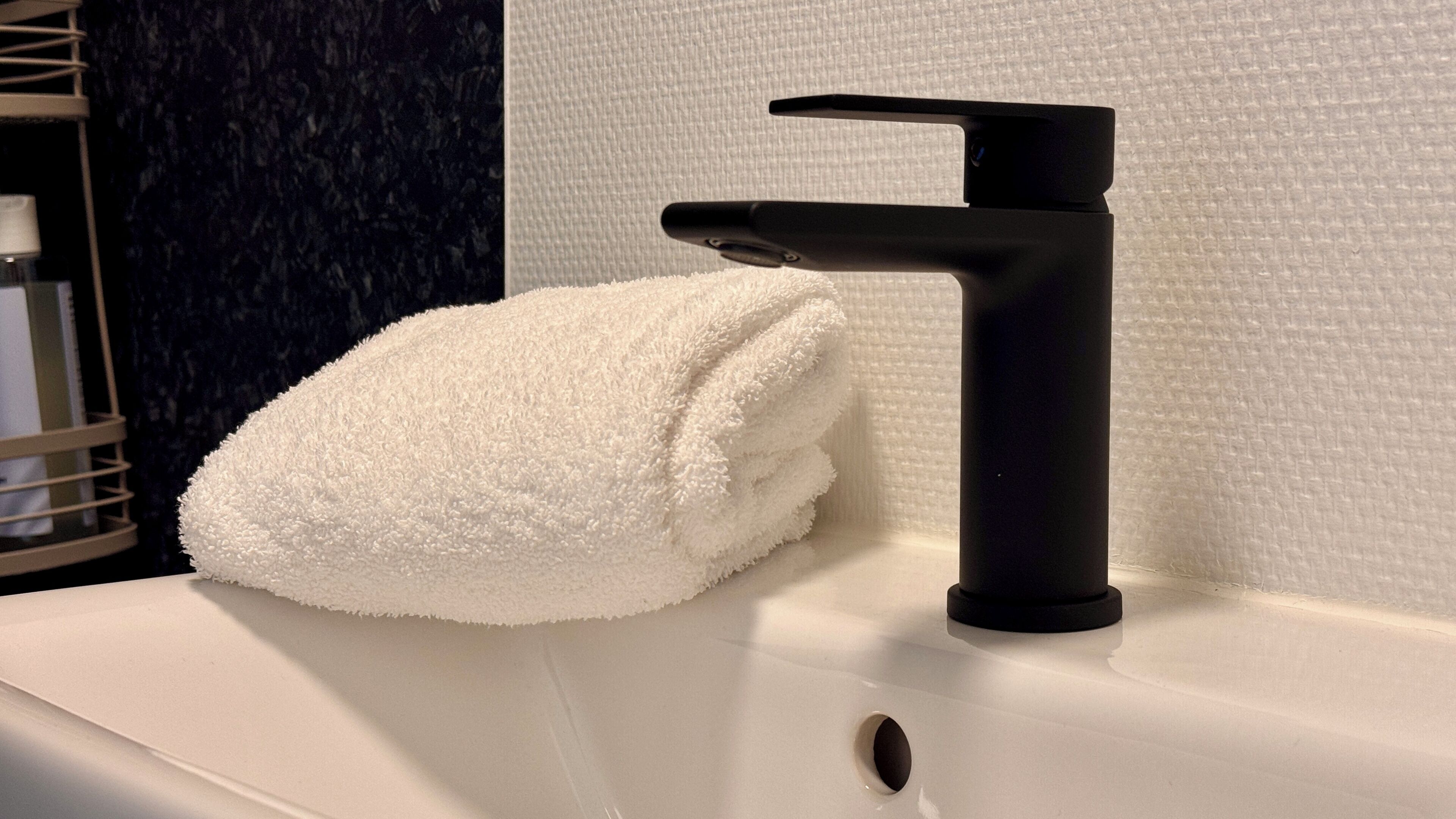 A bathroom sink with a black faucet and a white towel placed on it.