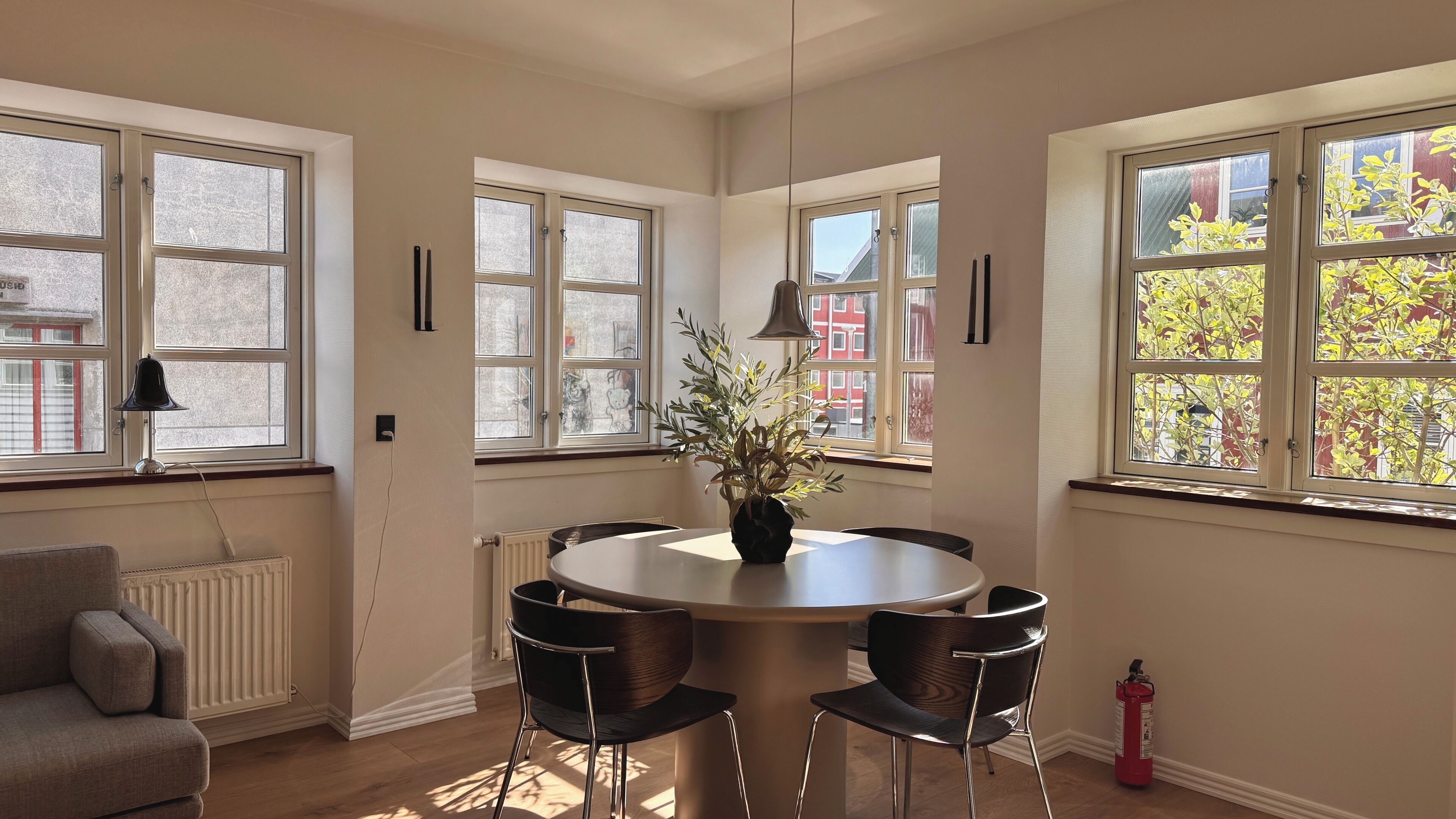 Un coin repas comprenant une table ronde, quatre chaises, une plante en pot et un extincteur.