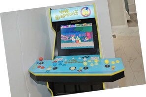 Máquina de videojuegos tipo arcade con la marca 'The Simpsons', mostrando una pantalla de fin de juego.