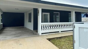 A two-story house with a covered porch, a chimney, and a white railing. - Modern Tropical Oasis with Full Solar Power & AC – Minutes from Beaches! (Fajardo)