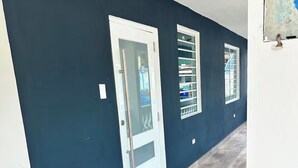 A hallway with dark blue walls, white-framed doors, and a grey patterned rug. - Modern Tropical Oasis with Full Solar Power & AC – Minutes from Beaches! (Fajardo)