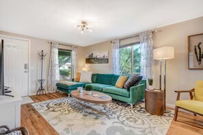 Ein Wohnzimmer mit einem grünen Sofa, einem Couchtisch, einer Lampe und einem Sessel.