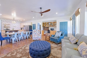 A spacious living area with a dining table, ottoman, sofa, and a ceiling fan. - Blue Willows : Alpine Escape Home (Oakley)