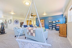 A living room with a hanging chair, a ceiling fan, a couch, and a bookshelf. - Blue Willows : Alpine Escape Home (Oakley)