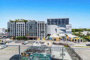 Een modern gebouw met meerdere verdiepingen, een parkeerplaats en een kleurrijke muurschildering aan de zijkant.