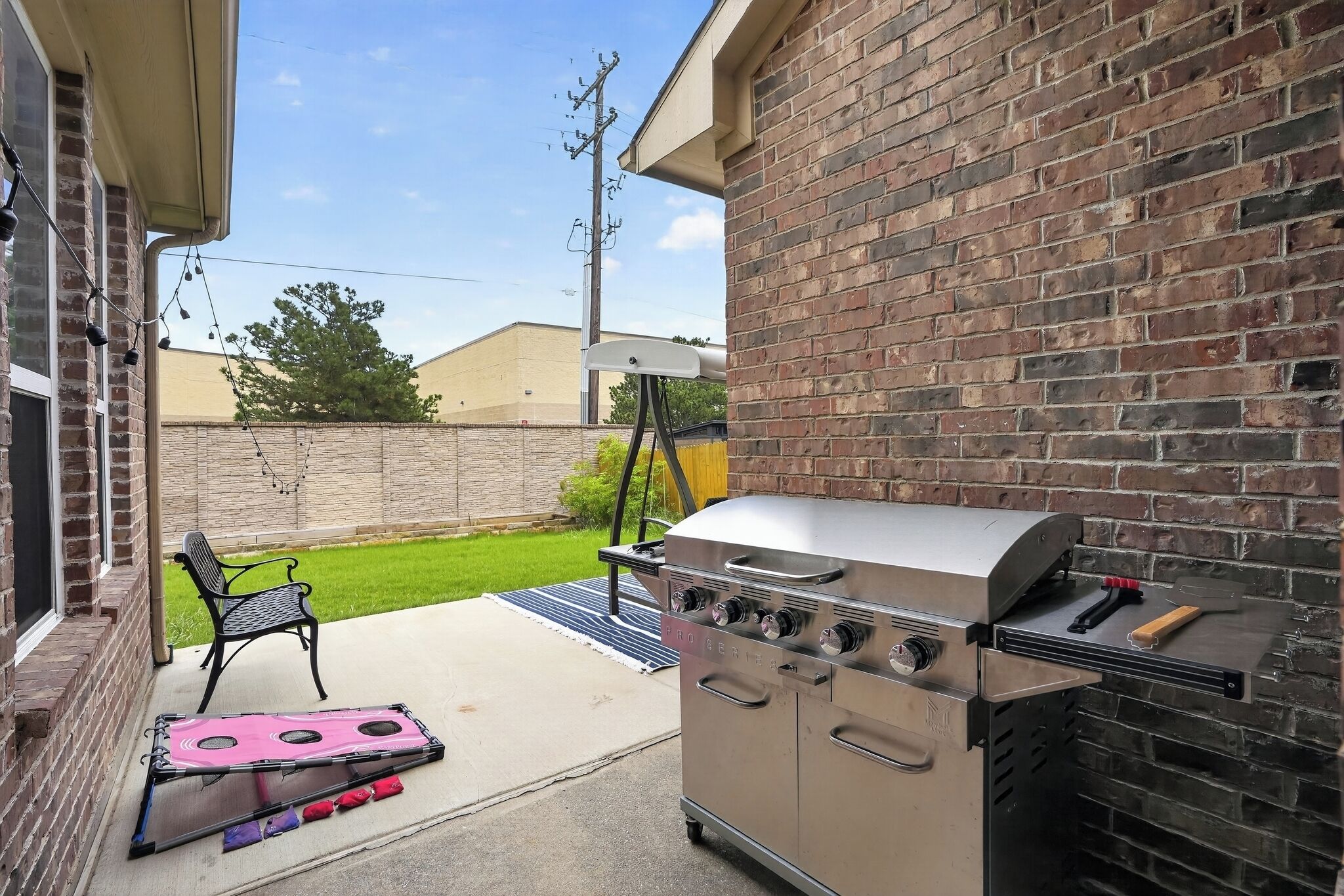 A patio with a barbecue grill, a folding table, and a chair.