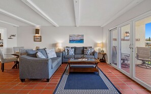 Ein Wohnzimmer mit grauem Sofagarnitur, einem Couchtisch und einem gemusterten Teppich.