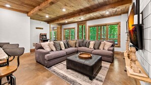 A modern living room with a sectional sofa, a coffee table, and a television. - Maison Bleue - Close to Downtown | Game Room | Firepit (Blue Ridge)