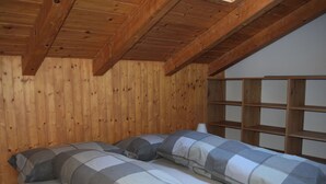 Una camera da chalet in legno con un letto a castello, travi in legno e soffitto spiovente.