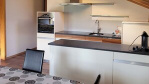 Una cucina moderna con forno integrato, lavello in acciaio inossidabile e soffitto in legno.
