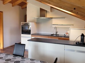 Una cocina moderna con horno empotrado, lavamanos y cafetera.