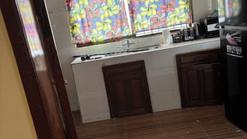 Una cocina con ventana, pileta, microondas y refrigerador.