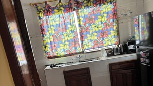 Una cocina con ventana, armarios de madera, un lavamanos y un refrigerador.