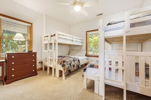 A bedroom with bunk beds, a dresser, a ceiling fan, and a window with blinds.