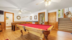 A pool table in a room with wooden floors, a ceiling fan, and a staircase. - Las Brisas: New Rental, Large Private Pool, Hot Tub (Corolla)