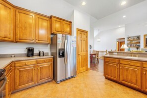 A kitchen with wooden cabinets, stainless steel appliances, and a tiled floor. - Las Brisas: New Rental, Large Private Pool, Hot Tub (Corolla)