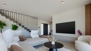 Uma sala de estar moderna com um sofá seccional, uma mesa de centro, uma TV de tela plana e uma escada.