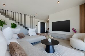 A modern living room with a sectional sofa, a coffee table, a flat-screen TV, and a staircase. - Villa Horizonte Verde (Istria - Motovun) (Motovun)