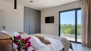 Quarto com cama, guarda-roupa, televisão e varanda com vista.