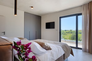 A bedroom with a bed, a wardrobe, a television, and a balcony with a view. - Villa Horizonte Verde (Istria - Motovun) (Motovun)