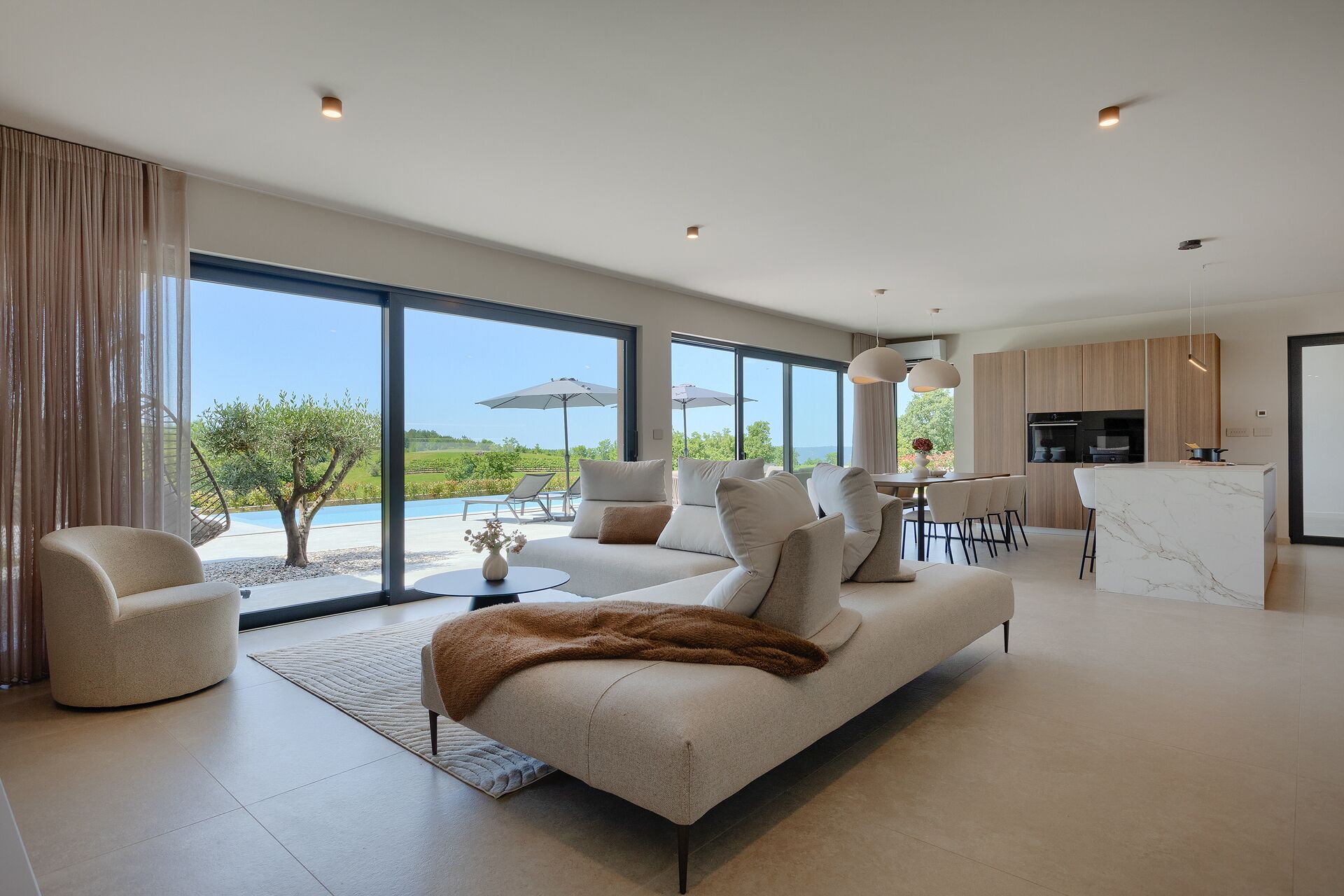 A modern living room with a sofa, a dining area, and a kitchen.
