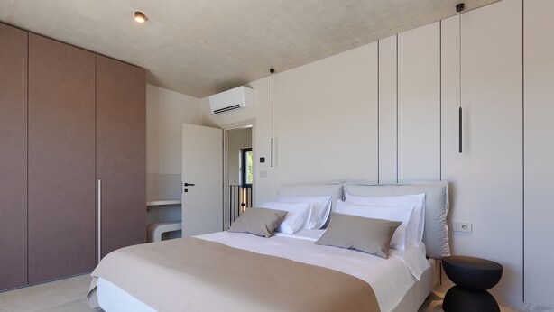 Quarto moderno com cama grande, guarda-roupa e ar condicionado.