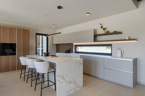 A modern kitchen with a marble island, bar stools, and built-in appliances. - Villa Horizonte Verde (Istria - Motovun) (Motovun)