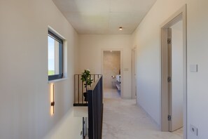 A hallway with a window, a plant, a door, and a bathroom visible in the distance. - Villa Horizonte Verde (Istria - Motovun) (Motovun)