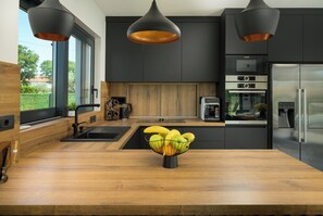 A modern kitchen with a wooden countertop, a fruit bowl, and stainless steel appliances. - Villa Luna Kanfanar (Istria - Kanfanar) (Kanfanar)