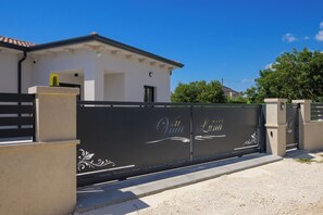 Una villa amurallada de aspecto blanco con un portón negro.