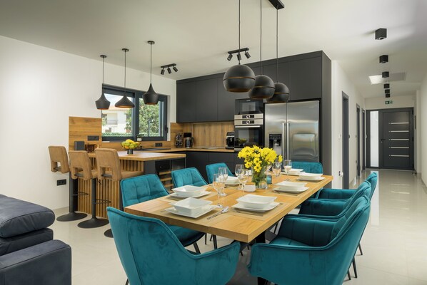 Una cocina moderna con comedor, sillas azul verdosas y una mesa de madera dispuesta para seis.