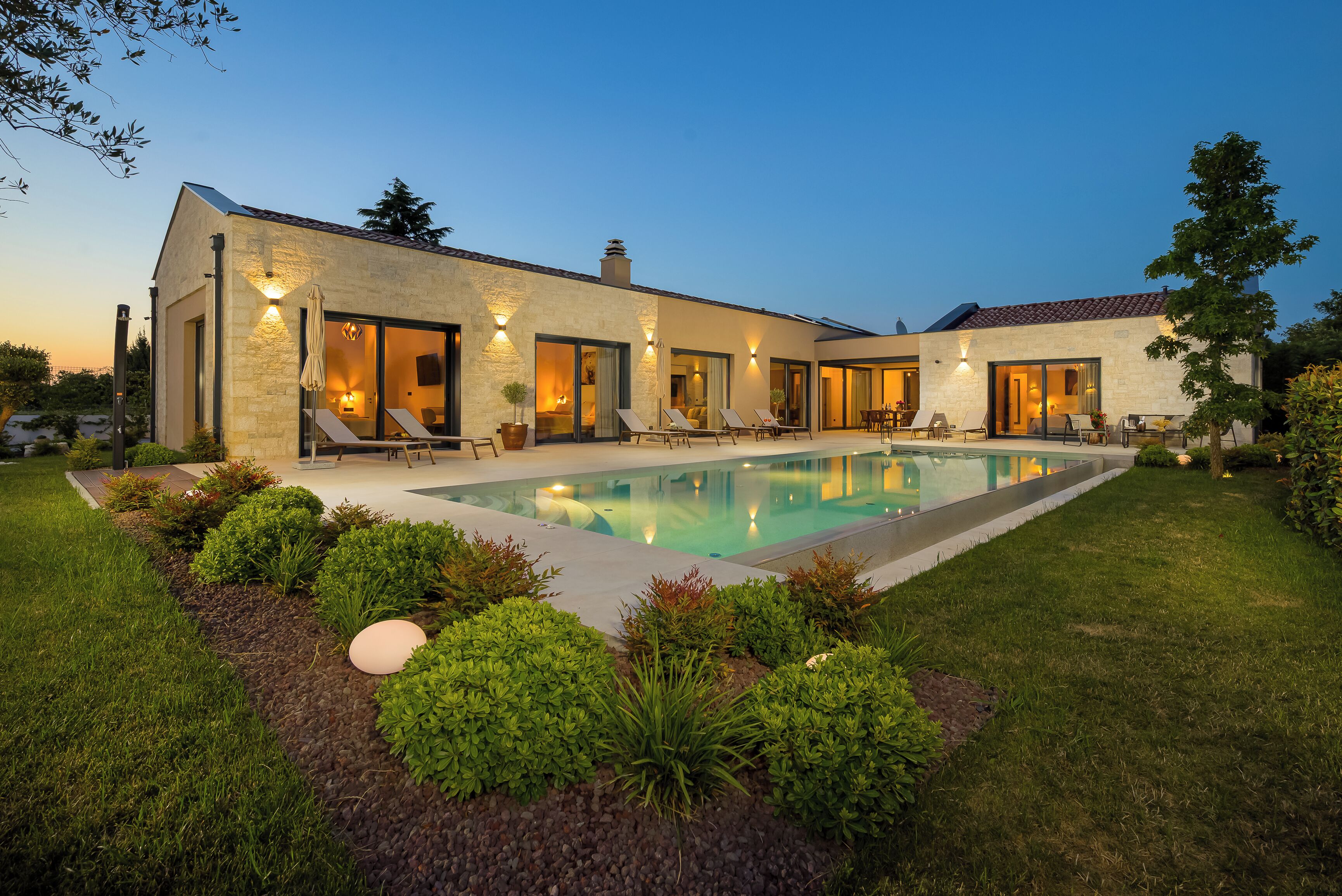 A modern house with a swimming pool, multiple entry doors, and outdoor seating.