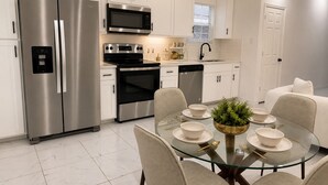 A modern kitchen with stainless steel appliances, a glass dining table, and a minimalist design. - NEW Spacious 3-bedroom in Dowtown San Antonio- RIVER WALK & FROST BANK CENTER (San Antonio)
