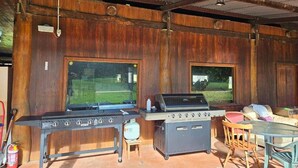Un patio al aire libre con una estación de barbacoa, una mesa y sillas.