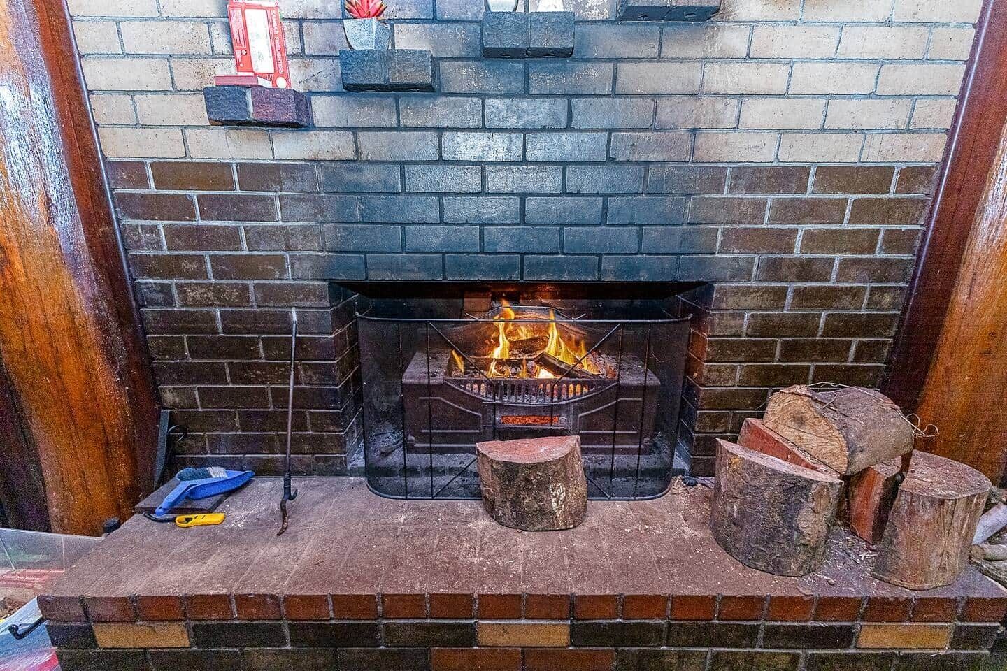 A fireplace with a fire, a wooden bench, and logs.