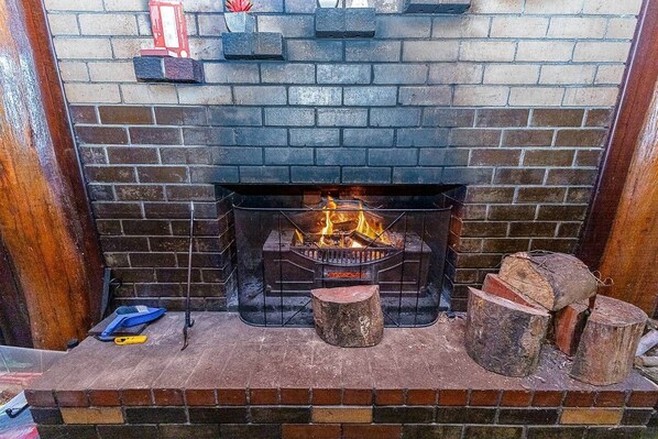 A fireplace with a fire, a wooden bench, and logs.