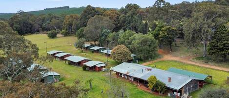 A rural property with multiple cabins, a large open field, and dense forest in the background.