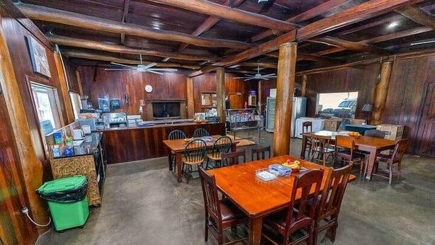 Un interior rústico de madera con una zona de bar, varias mesas de comedor y sillas.