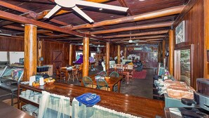 A rustic interior with wooden beams, a bar area, dining tables, and a seating area.
