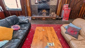 A living room with a fireplace, leather sofas, a wooden coffee table, and a red patterned rug.