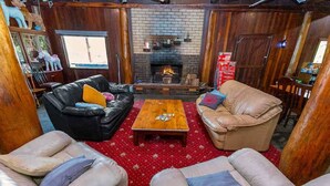 Una sala de estar acogedora con chimenea, sofás de cuero y una alfombra roja estampada.