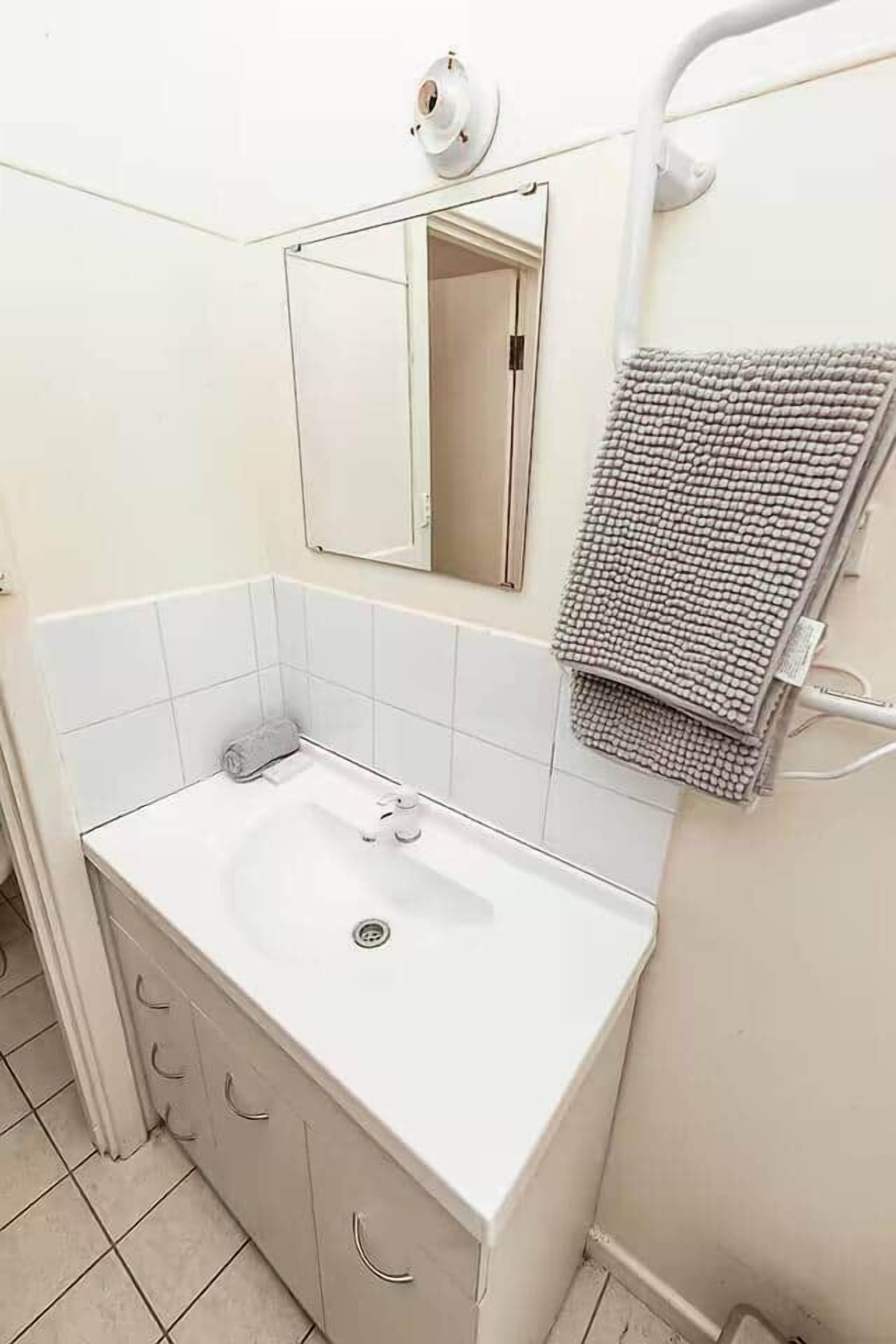 A bathroom with a white sink, a mirror, and a towel rack.
