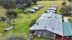 Propiedad rural con varias edificaciones de techo verde, un granero y vegetación circundante.