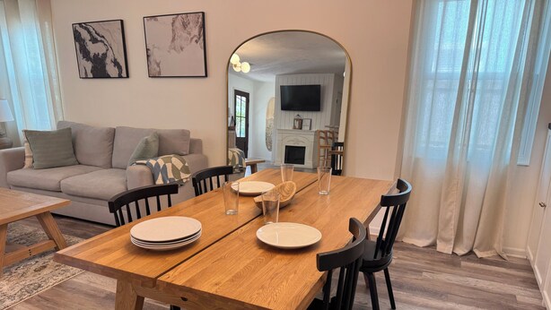 En matplats med ett träbord, svarta stolar och en spegel som reflekterar rummet.