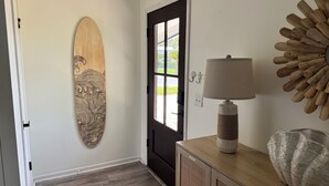 En hall med en surfbräda i trä, en dörr, en lampa och en dekorativ väggdekoration.