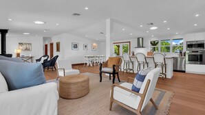 A spacious living area with a kitchen, dining area, and a large window providing a view of the outdoors. - Bleu Hermitage | Private 25-Acre Luxury Sanctuary (Naples)