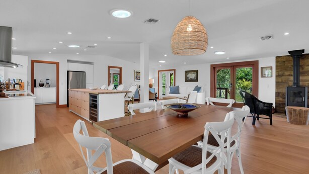 A spacious kitchen with white cabinetry, a wooden dining table, and a large island. - Bleu Hermitage | Private 25-Acre Luxury Sanctuary (Naples)