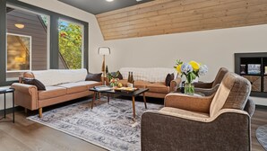 A modern living room with a sectional sofa, a coffee table, and a fireplace. - Alpine Evergreen | Upscale A-Frame | Pet Friendly Cabin in Helen, GA (Helen)