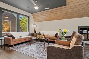 A modern living room with a sectional sofa, a coffee table, and a fireplace. - Alpine Evergreen | Upscale A-Frame | Pet Friendly Cabin in Helen, GA (Helen)