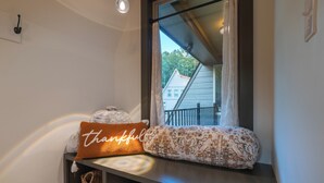 A bathroom with a window, a towel rack, and a shelf with towels and a pillow. - Alpine Evergreen | Upscale A-Frame | Pet Friendly Cabin in Helen, GA (Helen)